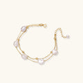 Double-strand gold bracelet with irregular baroque pearls and smooth freshwater pearls on cream background.