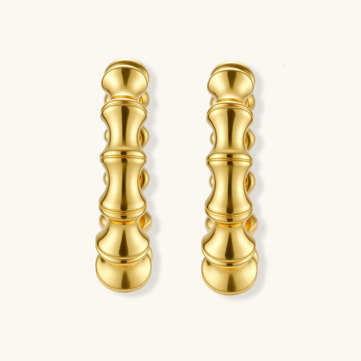 Close-up of gold-plated sterling silver hoop earrings with bamboo-inspired segmented design on white background.
