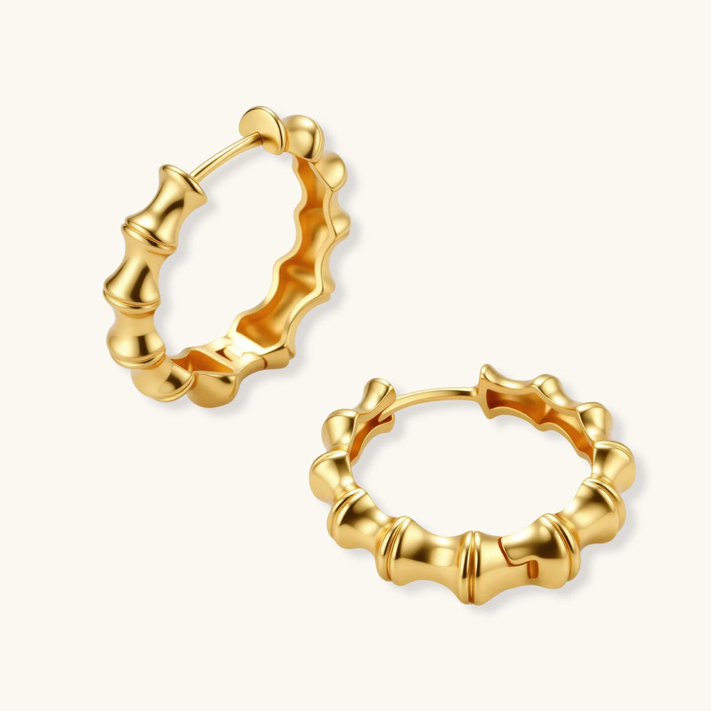 Close-up of gold-plated sterling silver hoop earrings with bamboo-inspired segmented design on white background.