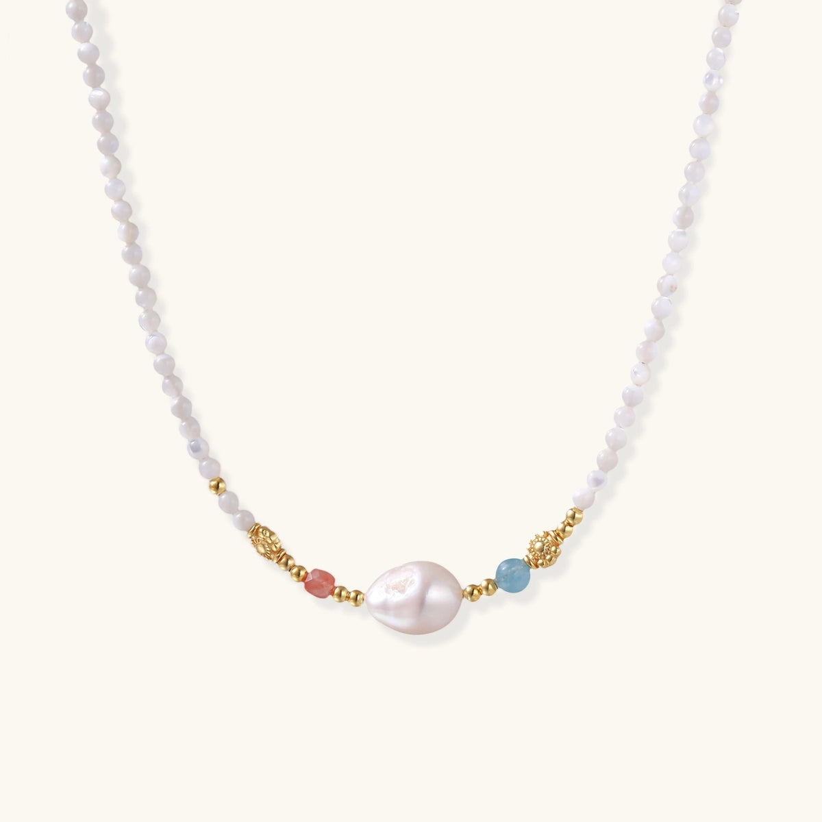 Dainty white beaded necklace with a central freshwater pearl, peach and blue beads and gold vermeil accents on a cream background.
