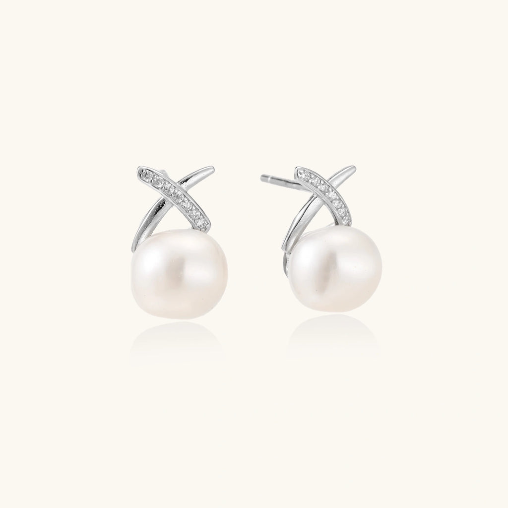 Rhodium-plated silver stud earrings with sparkling X design above lustrous round freshwater pearls on white background.