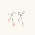 Rhodium-plated silver earrings with organic vine curves and two peachy freshwater pearls on cream background
