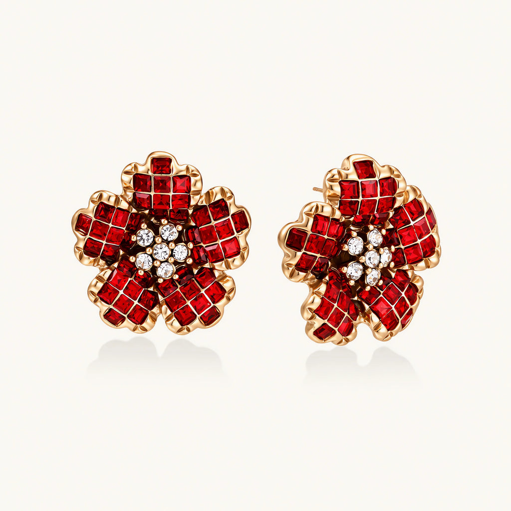 Gold-plated flower studs with burgundy square crystals in petal mosaic and clear center stones on beige background.