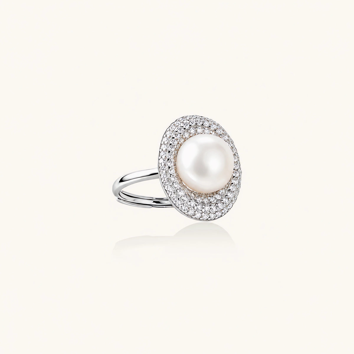 Silver ring with lustrous white pearl center surrounded by sparkling crystal halo on light background.