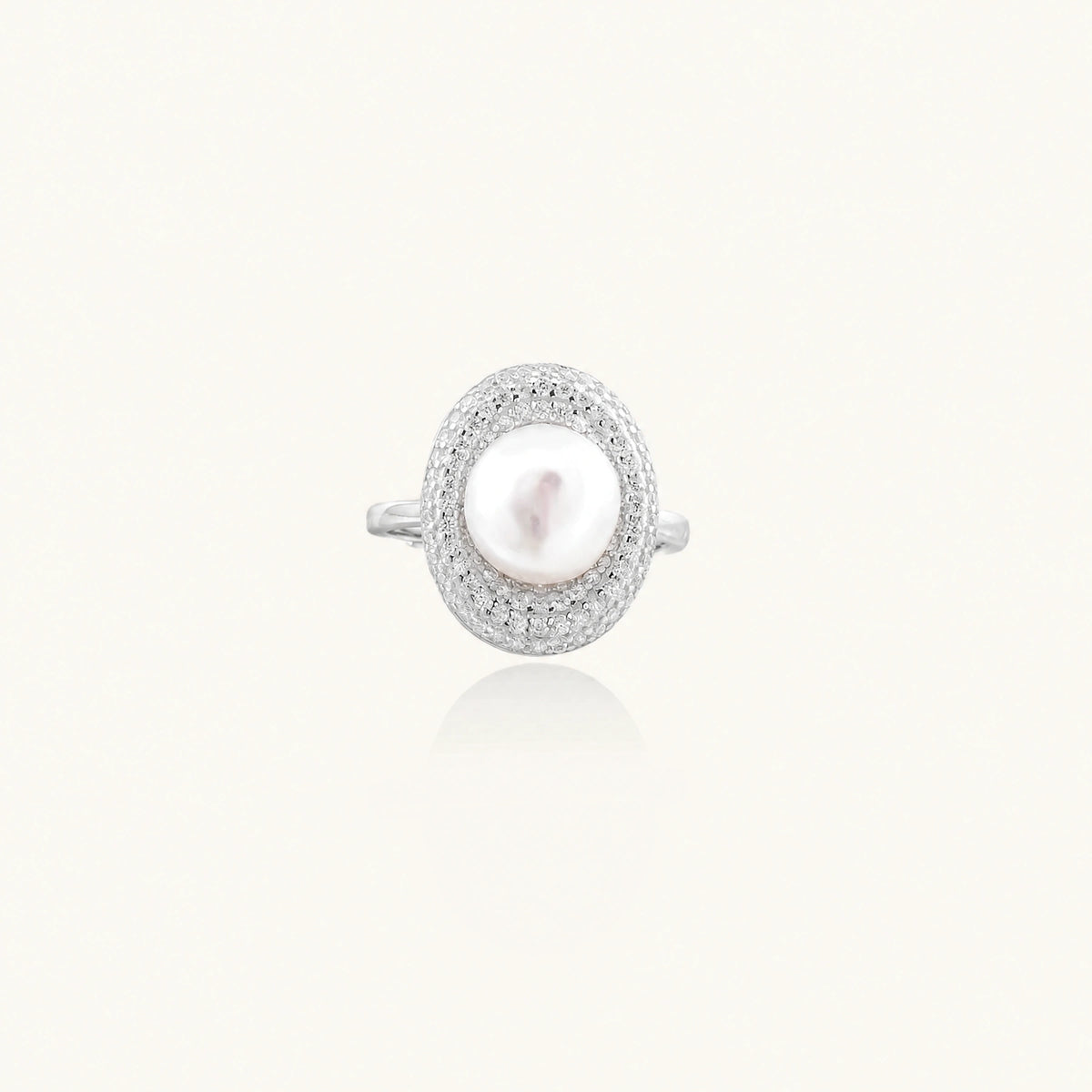 Silver ring with lustrous white pearl center surrounded by sparkling crystal halo on light background.