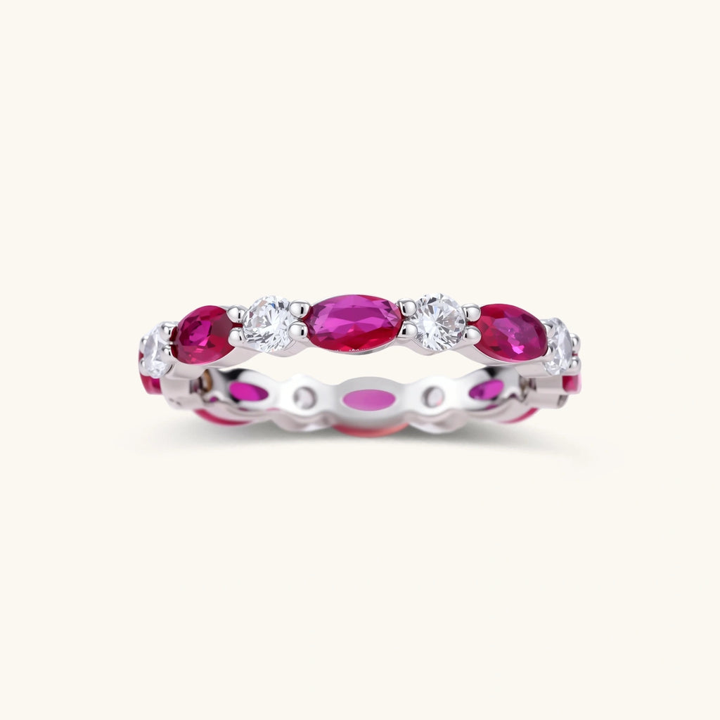 Platinum-plated eternity ring with alternating oval ruby and round clear stones in continuous band setting